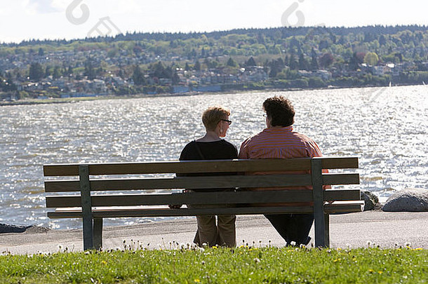 一对夫妇坐在海滩的长凳上