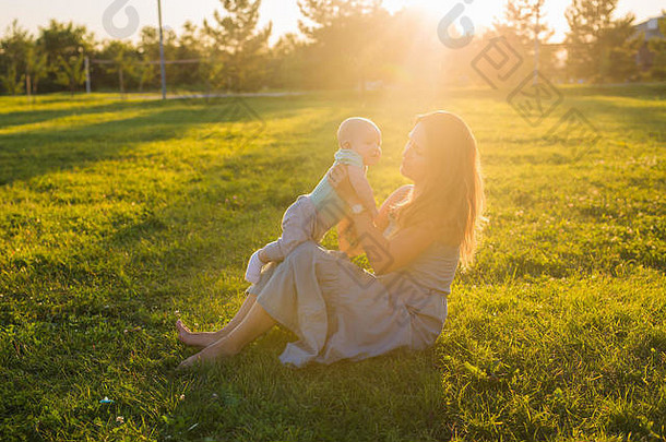年轻的女人男孩草地阳光明媚的一天快乐家庭夏天日落妈妈。婴儿