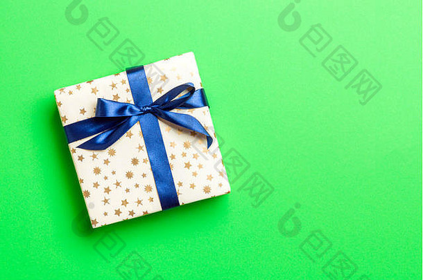用绿色背景上的蓝丝带用纸包装圣诞或其他节日手工礼品。礼品盒，彩台礼品装饰，t