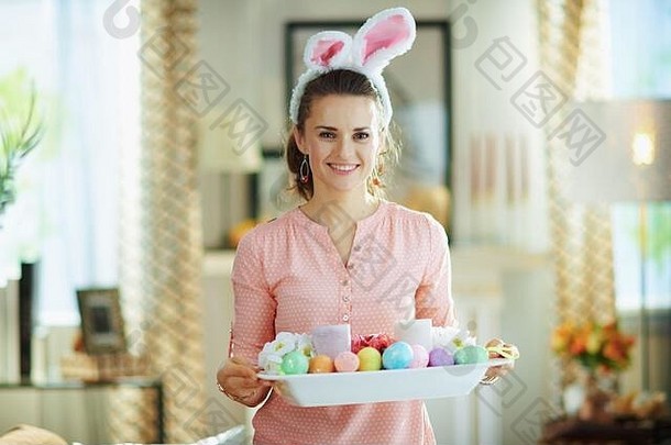 微笑中间年龄家庭主妇粉红色的上衣复活节兔子耳朵复活节装饰板现代生活房间阳光明媚的春天一天