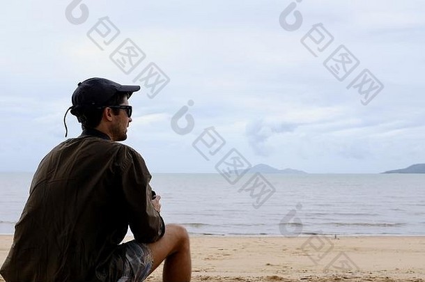 澳大利亚昆士兰卡德维尔，一名年轻男子坐在海滩上