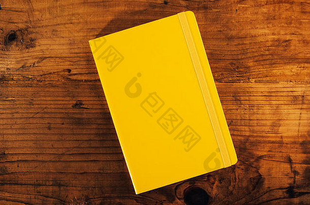 乡村木制办公桌上的黄色笔记本，俯视图，复印空间