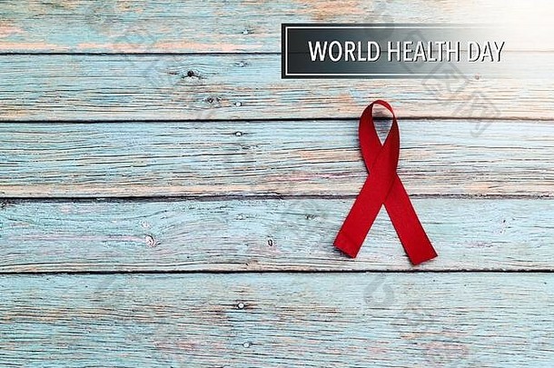 世界卫生日，医疗保健和医疗概念，蓝色木质背景上的红丝带