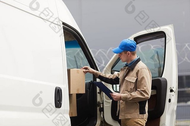 快递员在装运前检查车内的纸箱