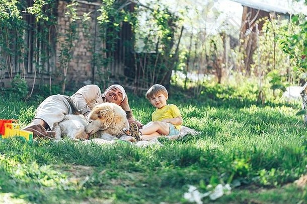 阳光明媚的日子里，快乐的祖父和孙子孙女以及一条狗躺在新鲜的草坪上