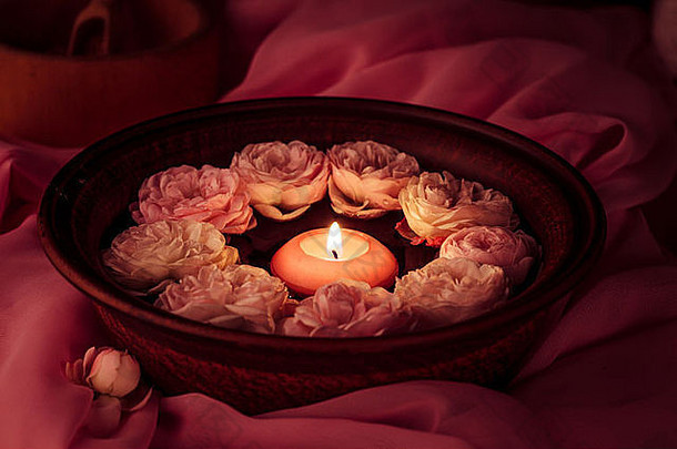 Spa放松-燃烧的蜡烛漂浮在玫瑰水中