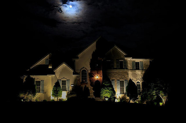 月亮照亮的房子；屋顶上云层后面的月亮