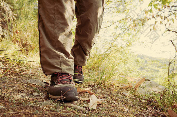 有红色鞋带和腿的<strong>登山鞋</strong>，穿着一条长长的棕色长裤，就像一个徒步旅行者在树林里的小路上行走一样。复古效应