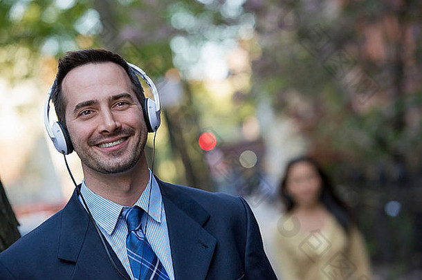 一个穿着西装的男人戴着白色耳机听音乐。