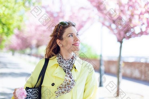 年轻的美丽的红色头发的人高加索人女人走公园春天樱桃树盛开的