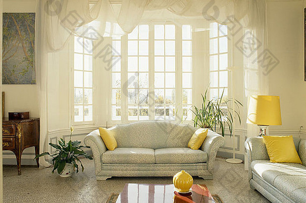 平台地板上灰色沙发黄色的垫子传统的法国生活房间帆窗帘湾窗口