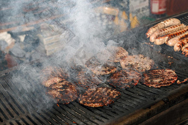 汉堡是在露天烤架上烹制的，冒出大量的烟。