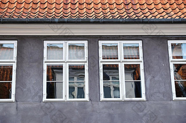 灰色灰泥外墙，白色双平开窗，木质，上面是红色粘土瓦屋顶和锌制排水沟