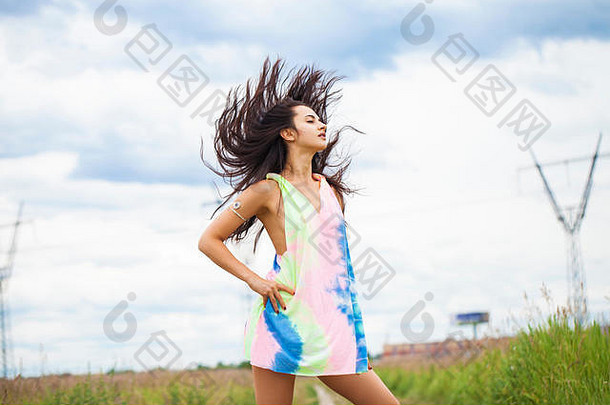 一位身穿彩色束腰外衣的年轻美丽女子的肖像，在草地的背景下摆姿势