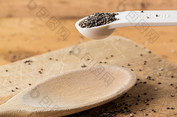 被称为黑芥籽的超级食品，用白色塑料量匙盛在厨房餐桌上的木面包板上
