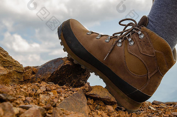 脚踩在石头和橘子土表面上的登山鞋