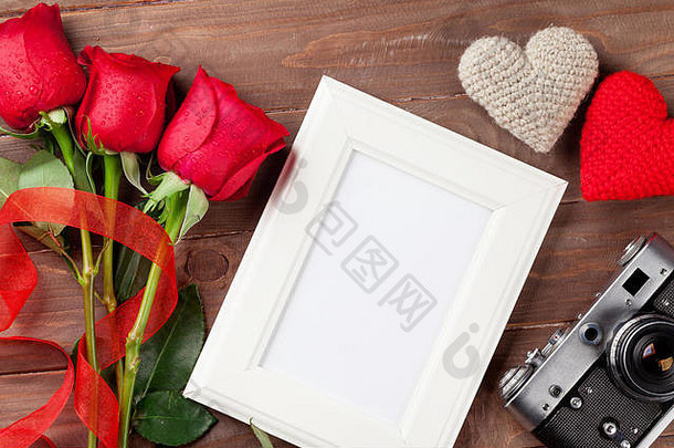情人节玫瑰、相框、复古相机和木制背景上的心形图案