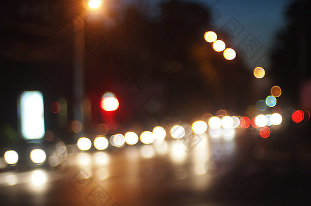 夜景的散焦和模糊-车灯亮着的汽车在城市道路上迎着夜空行驶