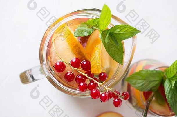 罐装新鲜桃子柠檬水，白底点缀浆果、醋栗、薄荷。夏日饮料。从上面看。闭合。