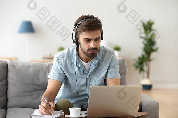 严肃的男子戴着耳机看着笔记本电脑学习<strong>外语</strong>