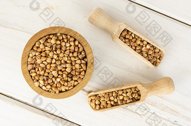 将整粒生的棕色<strong>荞麦</strong>粒放在一个木碗里，用木勺平放在白木上