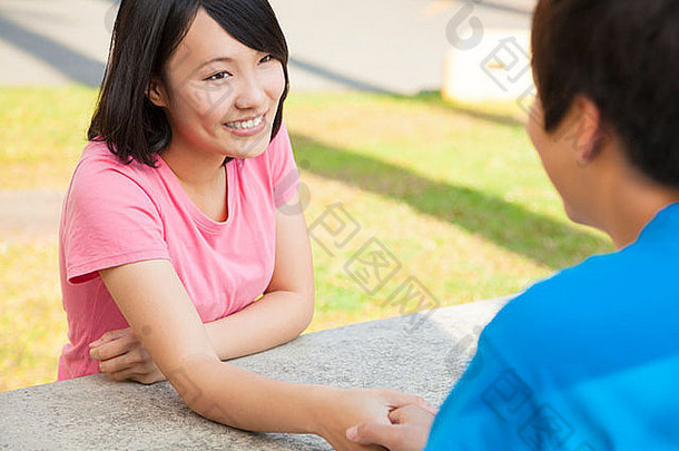 一对年轻夫妇手牵手坐在公园里