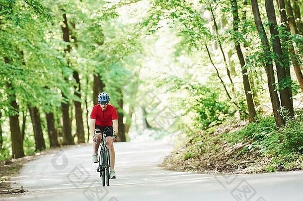 <strong>移动活动</strong>。在阳光明媚的日子里，骑自行车的人在森林里的柏油路上