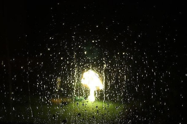 雨水滴在窗户玻璃上，光线在背景中反射。