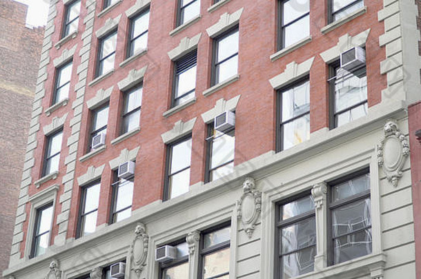 典型的纽约市风格红砖公寓楼的外观照片。窗式空调，为室内夏季降温