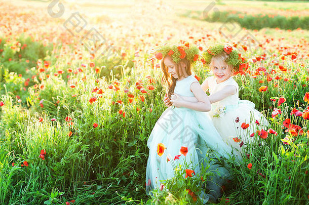 小女孩模特，婚礼，花，夏季时尚概念-两个女孩穿着婚纱在阳光明媚的花田里玩耍，两个笑着戴着夏季花环的女孩手牵手。