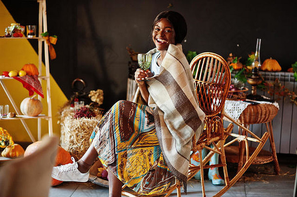 非洲裔美国女孩坐在摇椅上，对抗着秋意装饰。非洲的秋天。