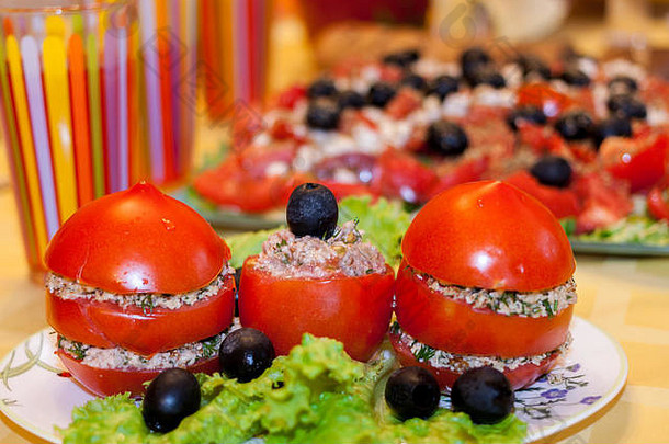 白色盘子里塞满了米饭、生菜和橄榄的红色西红柿，背景是希腊沙拉。