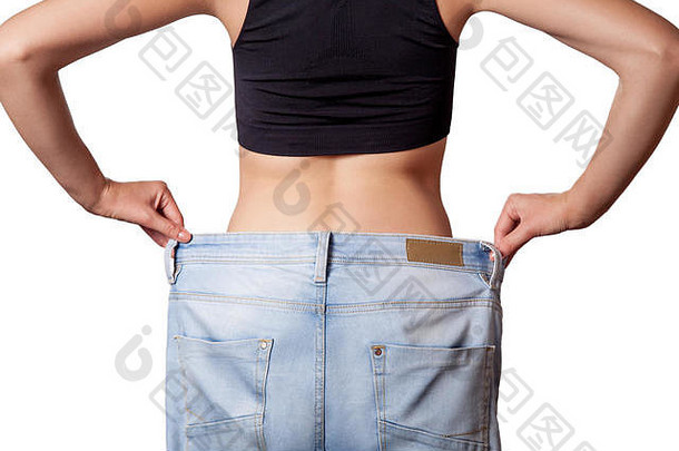 特写镜头苗条的腰年轻的女人大牛仔裤显示成功的重量损失孤立的白色背景饮食概念