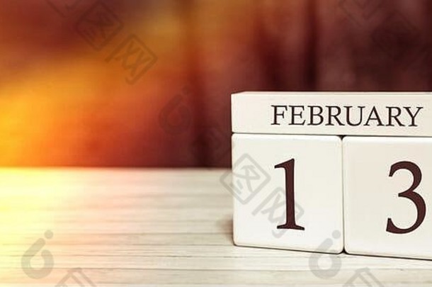日历提醒事件概念。2月13日，阳光照射下，带数字和月份的木制立方体。