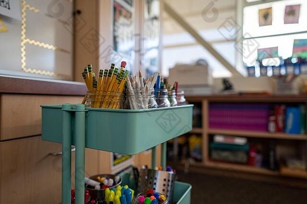 小学教室里装满各种艺术用品的手推车，如彩色铅笔和马克笔