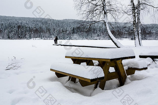 人景观木板凳上表格覆盖雪前面冻湖冬天野餐