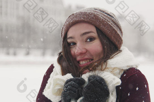 一个微笑的年轻女子站在冬天的外面。戴着白围巾