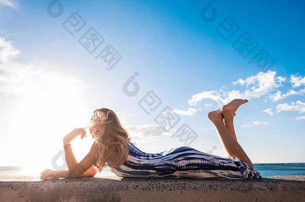 长头发西班牙语年轻的女人erlaxing躺墙海滩阳光美脸微笑享受时间
