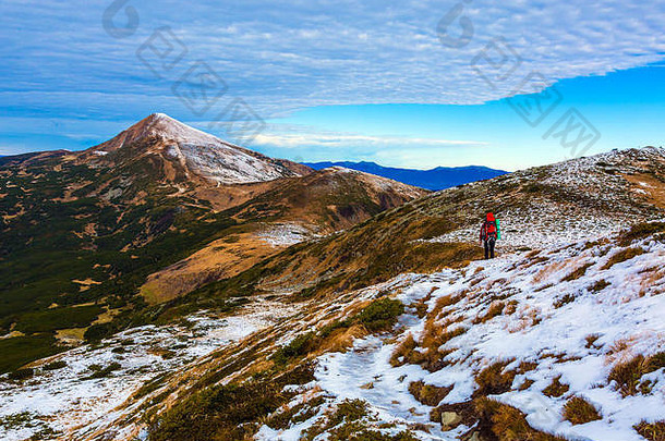 远足者行走在雪坡上，山堆在远处
