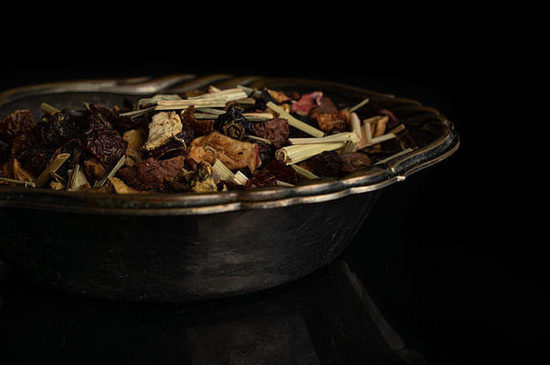 在一个旧铁碗里，在黑玻璃上分离出许多片林根莓草莓水果茶