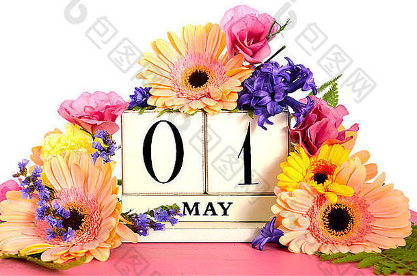 五一节快乐复古木日历，粉红色木桌上装饰着春天的花朵。