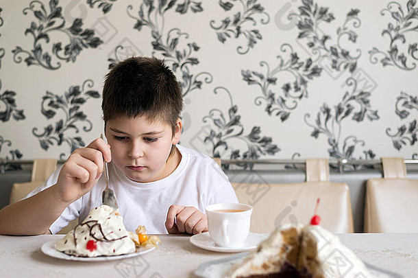 男孩在桌上用蛋糕喝茶