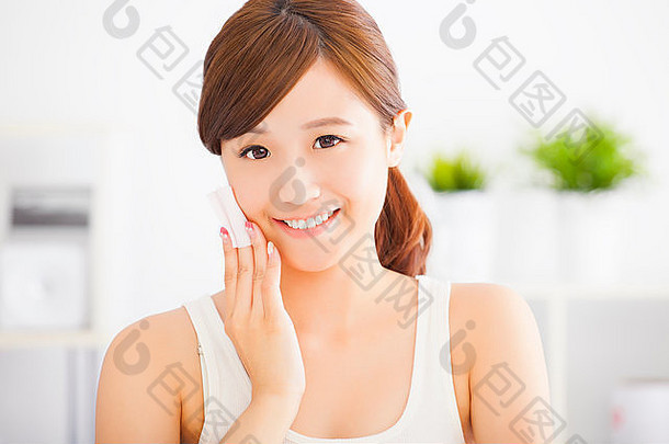 美丽的亚洲年轻女子用棉花擦脸