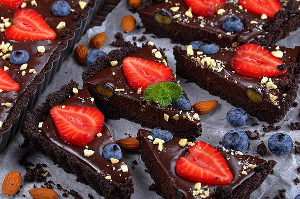 美味的甜蜜的烤巧克力蛋挞巧克力巧克力酱新鲜的蓝莓草莓装饰细切碎杏仁烘焙壳牌