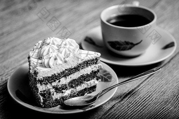 黑白照片。放在一个木制的盘子上，上面放着蛋糕、茶杯和勺子