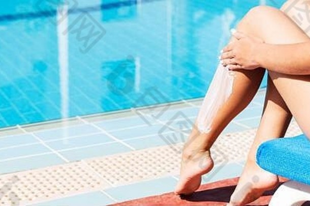 晒黑女人坐着游泳池应用<strong>防晒霜</strong>保护皮肤晒伤太阳保护因素假期概念