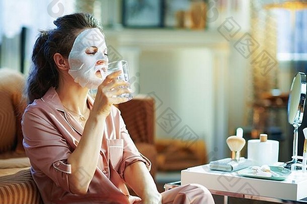 优雅的女人睡衣白色表面部面具脸喝水现代首页阳光明媚的冬天一天