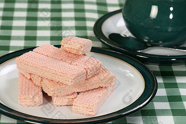 一堆粉红色的饼干放在一个绿白相间的盘子里