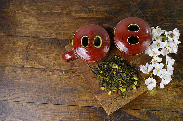 日本的茶杯，木质木板上有绿茶，深色木质背景上有樱花