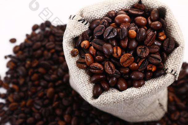 咖啡豆从黄麻袋或小袋中溢出的照片，拍摄于白色背景上